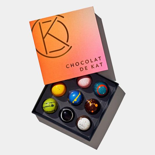 Box of colorful chocolates with 'Chocolat de Kat' branding for delivery or pickup in Toronto.