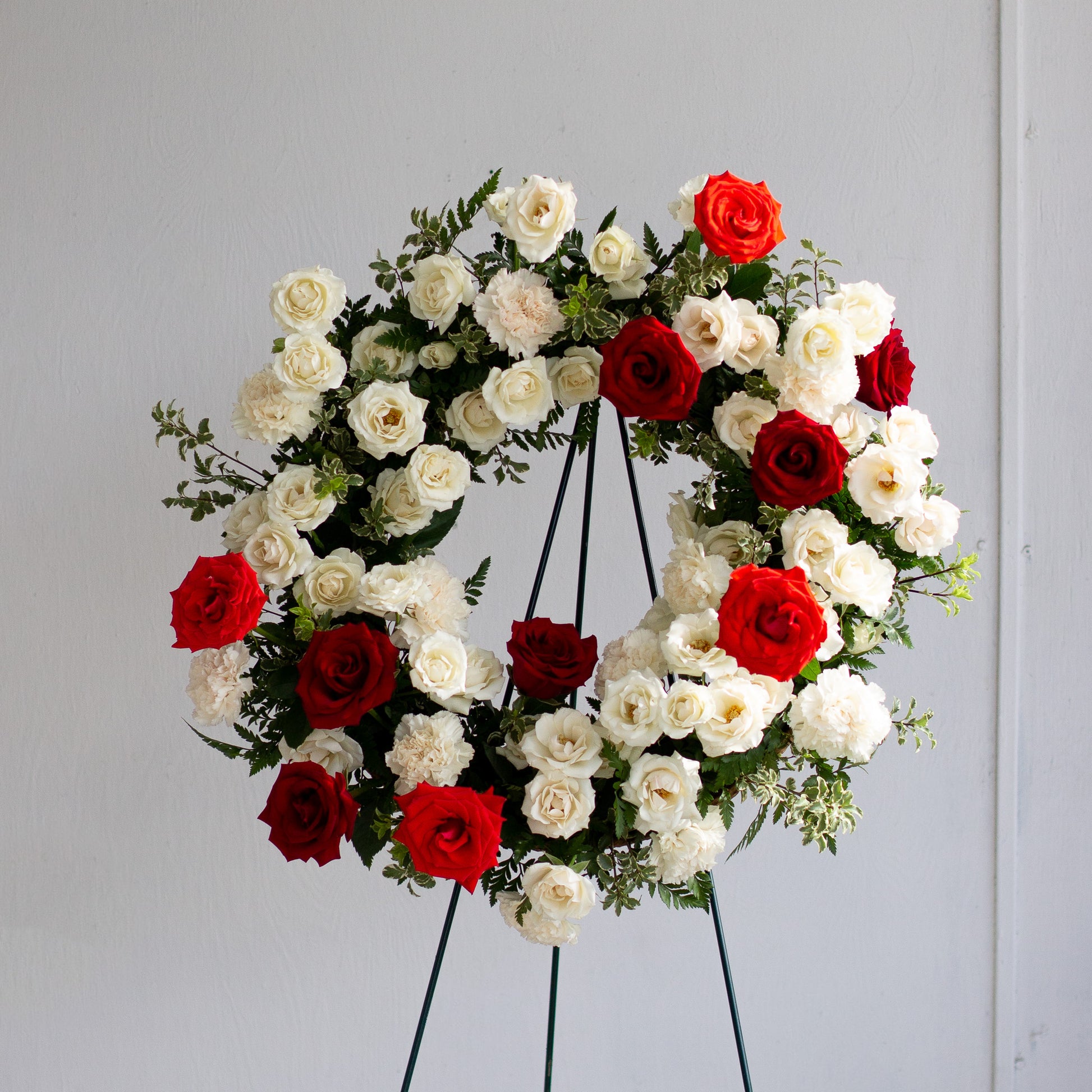 Red and white rose wreath on stand by Annam Studio, Toronto floral arrangement.