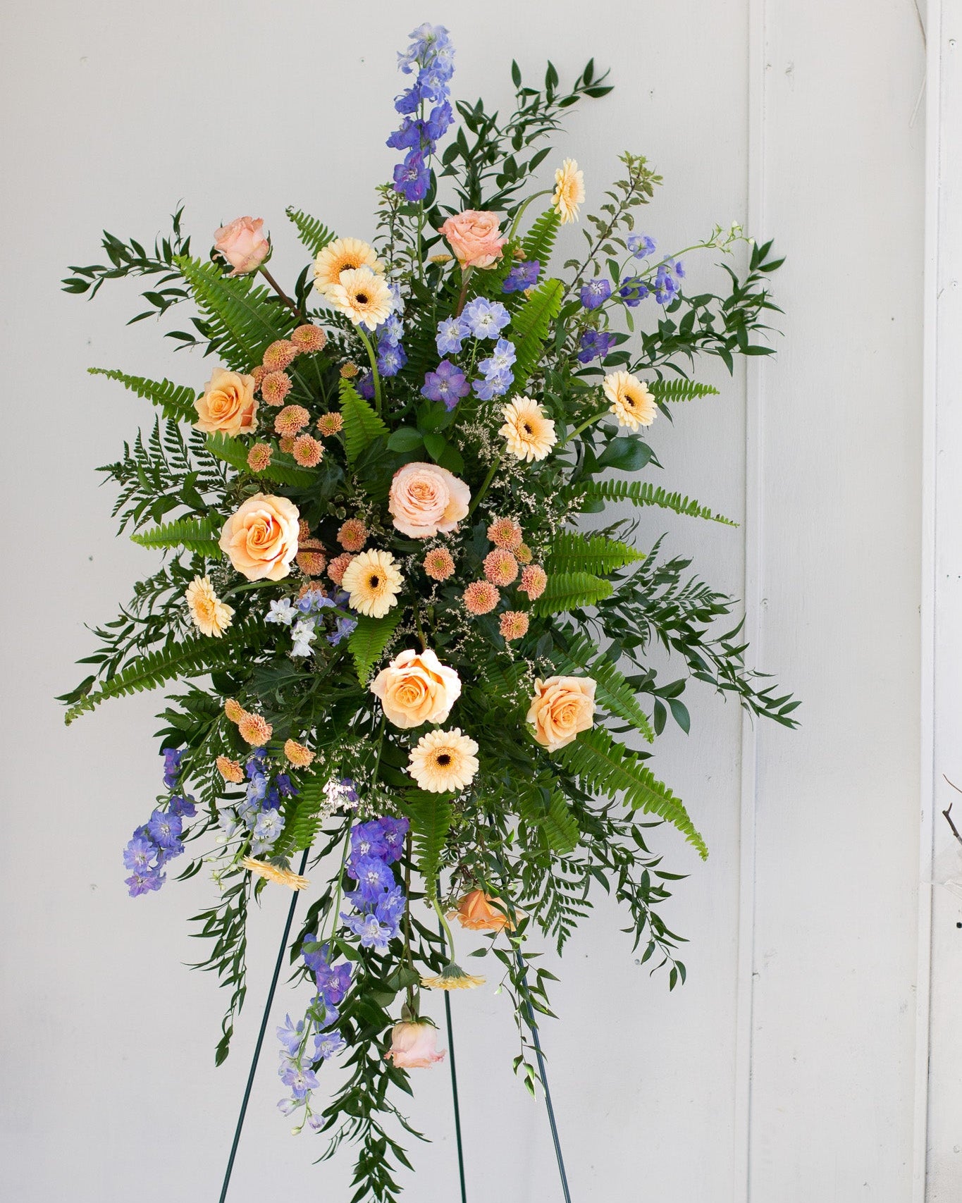 Standing spray arrangement with peaches, purples, greens and yellows for delivery or pickup in Toronto.
