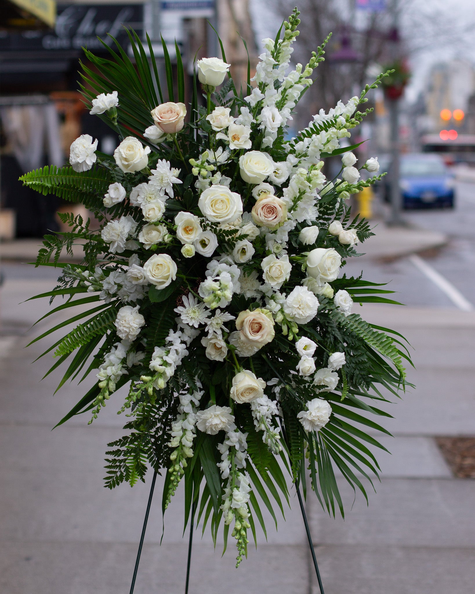 Standing spray floral arrangement with white flowers and greenery for delivery or pickup in Toronto.