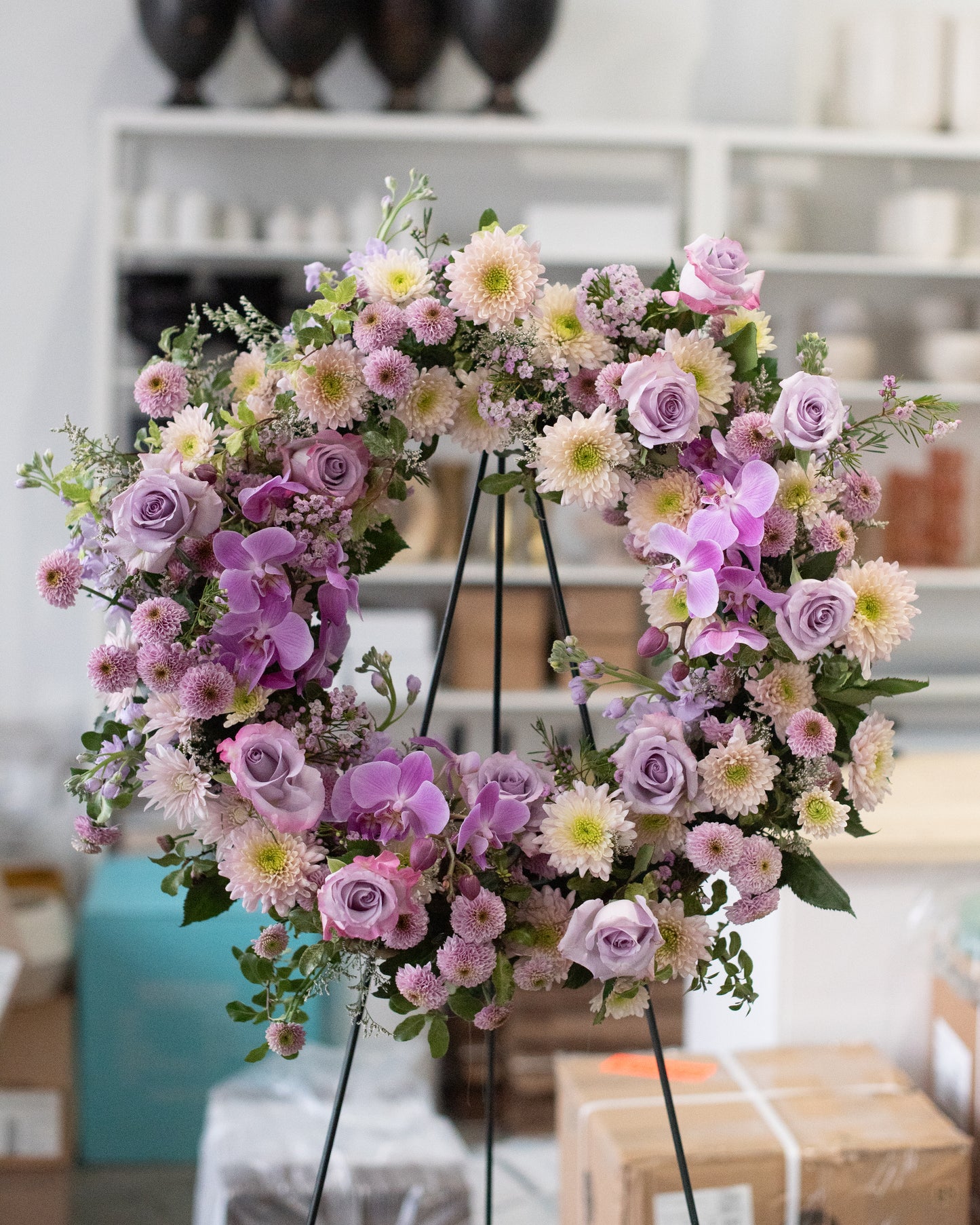 Floral wreath with pink and purple flowers on a stand for delivery or pickup in Toronto.