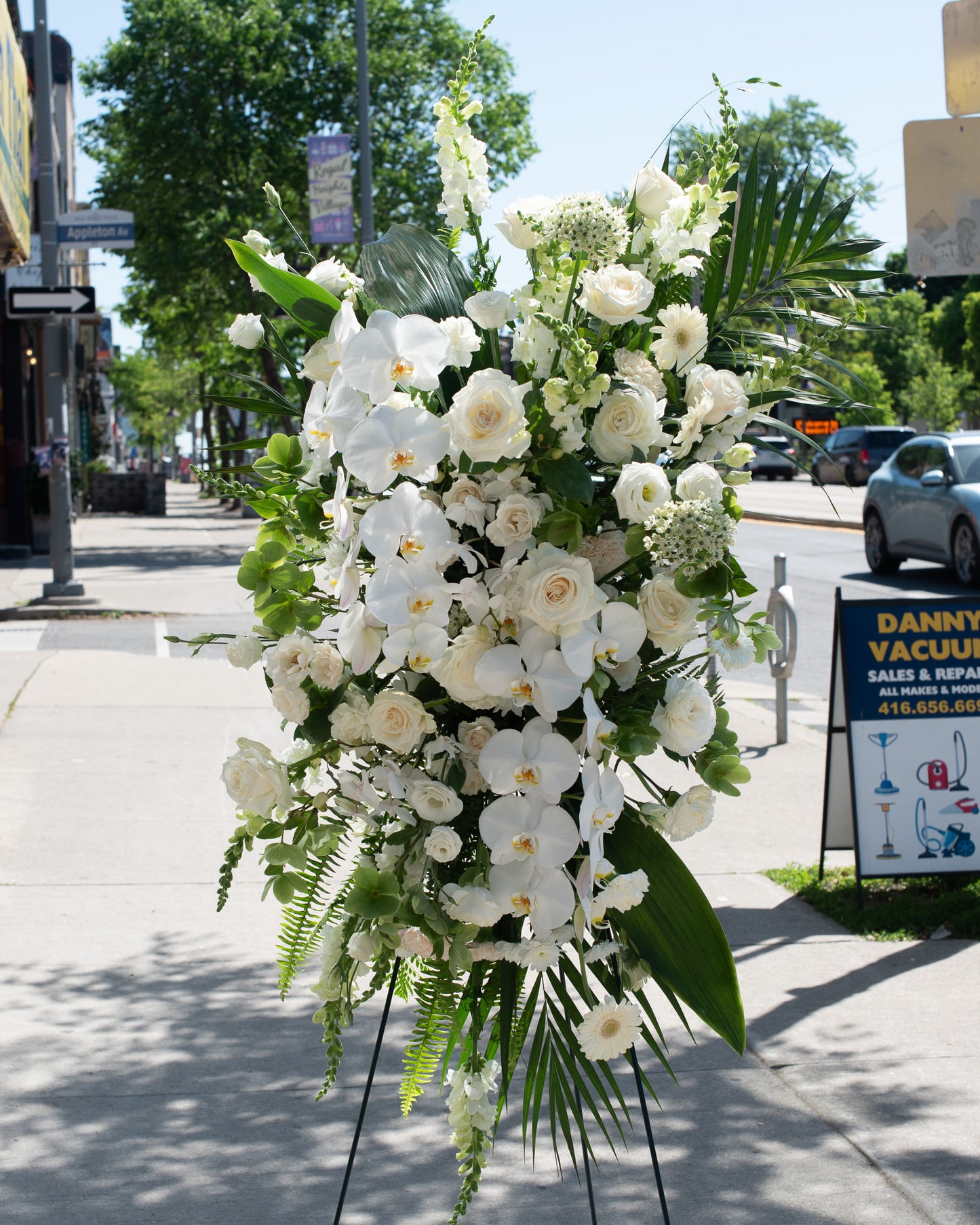Large white floral arrangement with greens on a stand for delivery or pickup in Toronto.