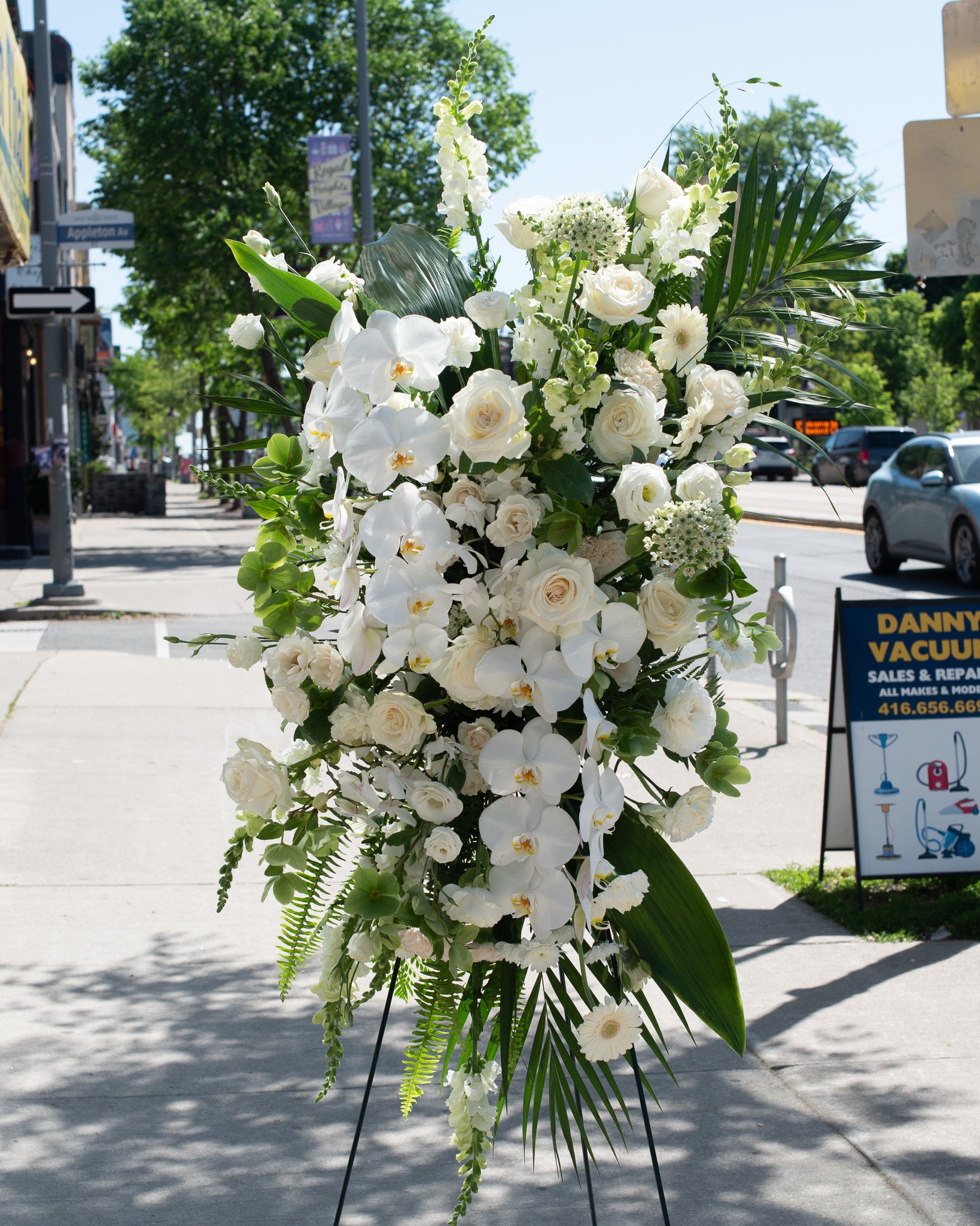 Large white floral arrangement with greens on a stand for delivery or pickup in Toronto.