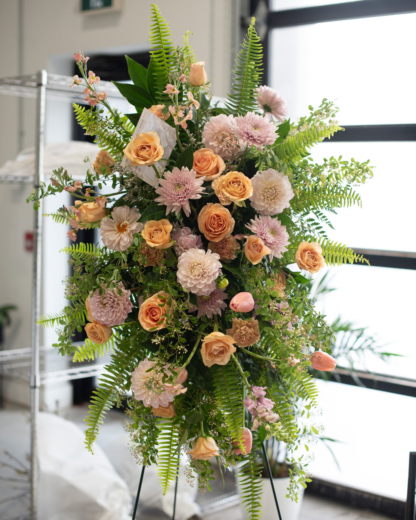 Floral arrangement with pink, orange, and green flowers on a stand for delivery or pickup in Toronto.