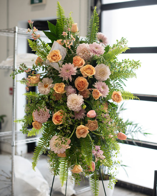 Floral arrangement with pink, orange, and green flowers on a stand for delivery or pickup in Toronto.