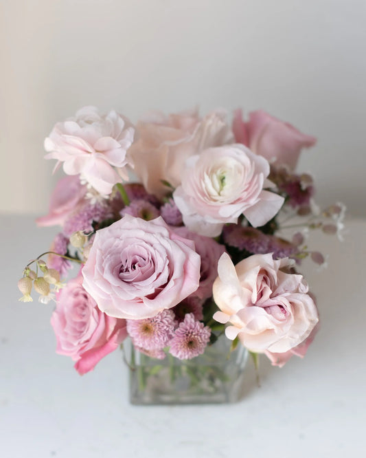 Modern pink rose and ranunculus floral arrangement in square glass vase by Annam Studio
