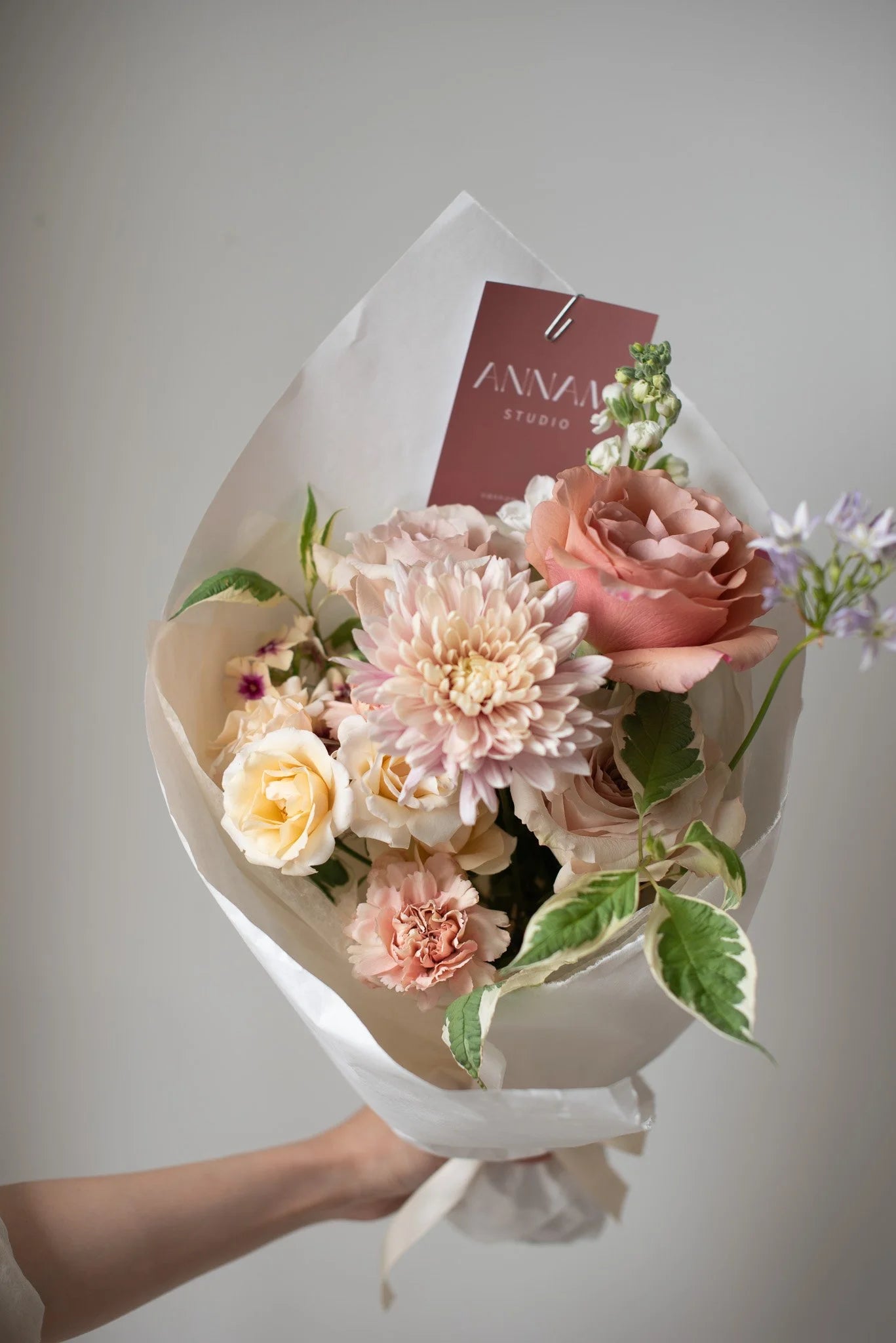 Hand holding modern pastel flower bouquet with roses and chrysanthemum from Annam Studio Toronto