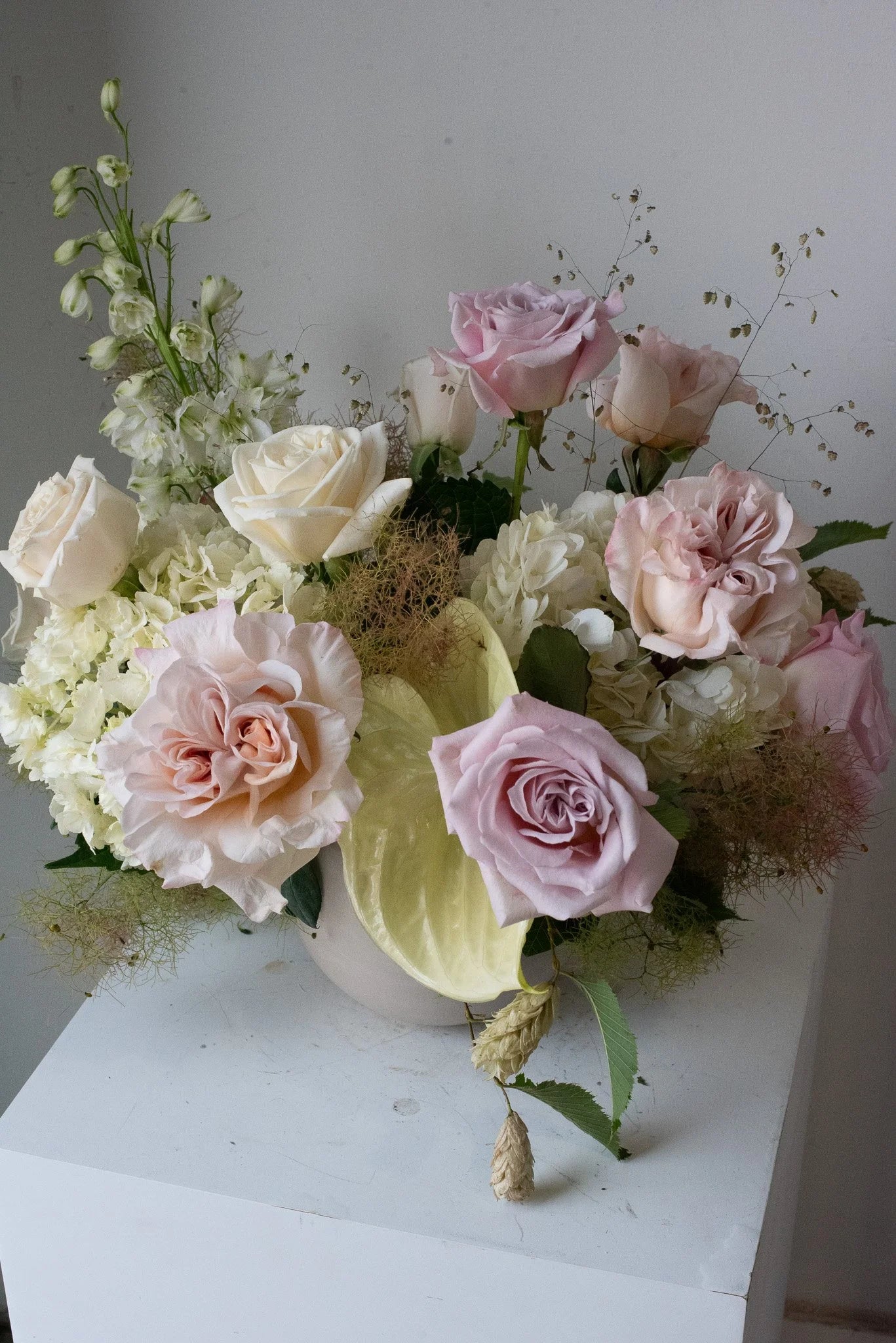 Modern pastel floral arrangement with pink roses by Annam Studio Toronto on white pedestal