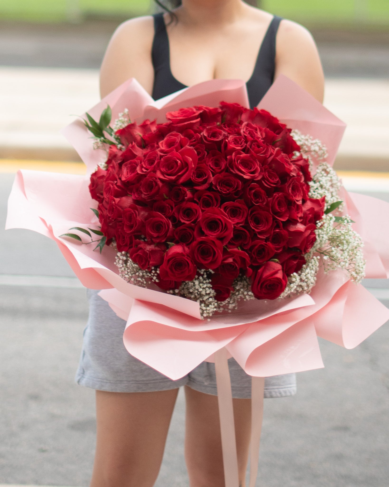 A large bouquet of 100 red roses wrapped in pink paper for delivery or pickup in Toronto.