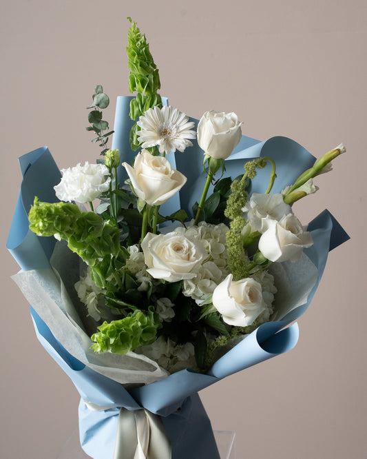 Modern white flower bouquet with roses and greenery in blue wrap from Annam Studio Toronto
