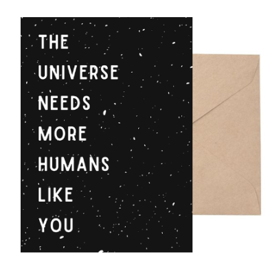 Card with 'The Universe Needs More Humans Like You' text on a black background with white specks, next to a brown envelope for delivery or pickup in Toronto.